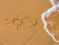 imagen de un sol y la letra d dibujado en la arena haciendo referencia a la vitamina d